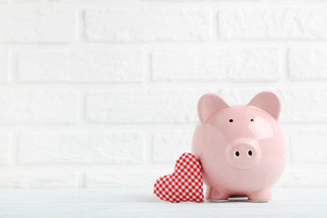 Pink piggy bank with red heart on white brick wall background