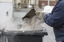 Man Throwing Ashes In A Trash Bin.
