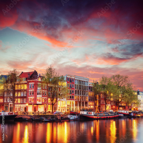 kanal-w-amsterdamie-plynacy-kolo-kolorowych-kamienic-na-tle-rozowego-wieczornego-nieba