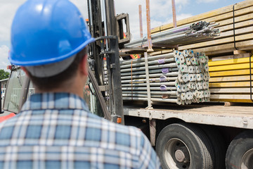 rear view of man looking at lorry load of materials