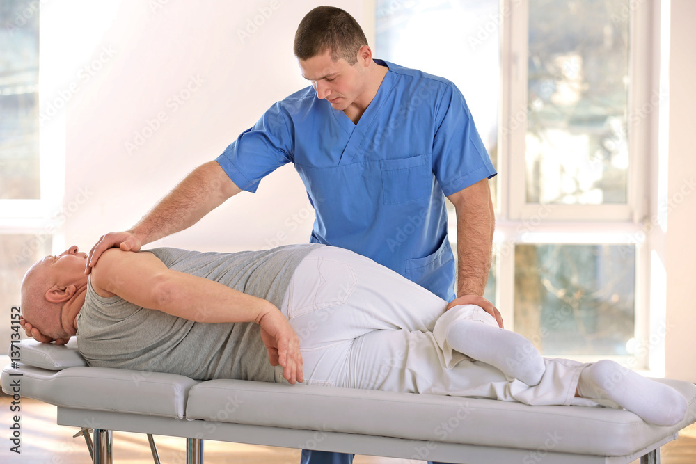 Physiotherapist working with elderly patient in clinic