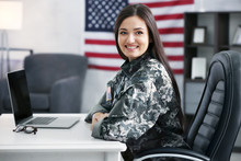 Pretty Female Soldier Working With Laptop While Sitting At Table In Headquarters Building