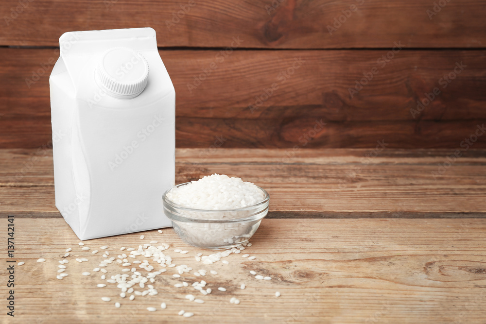 Simple milk box and little bowl with rice on wooden background