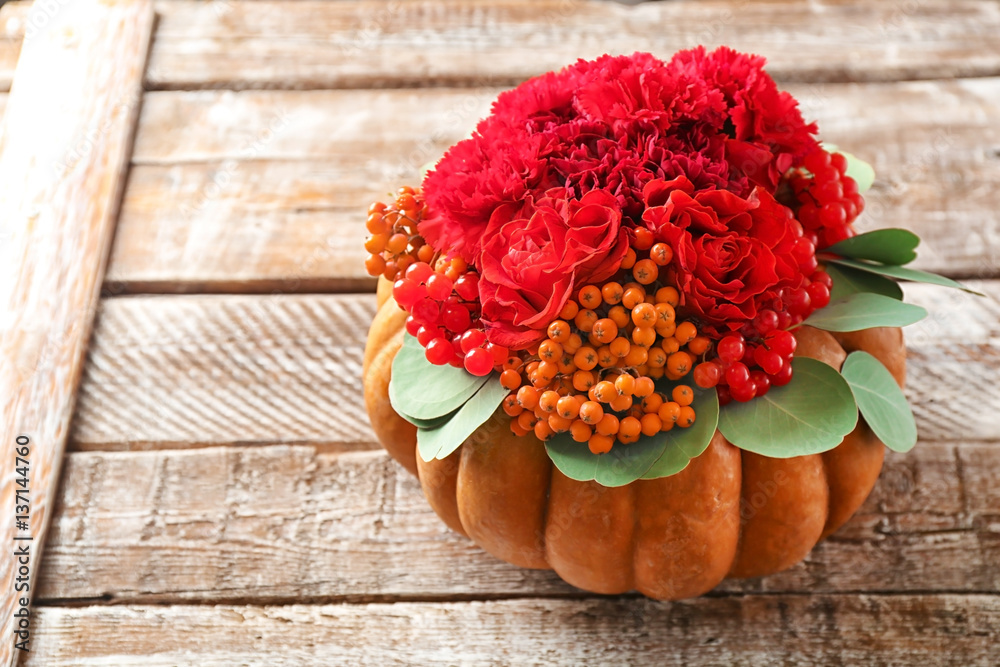 Pumpkin with flowers and berries on wooden background