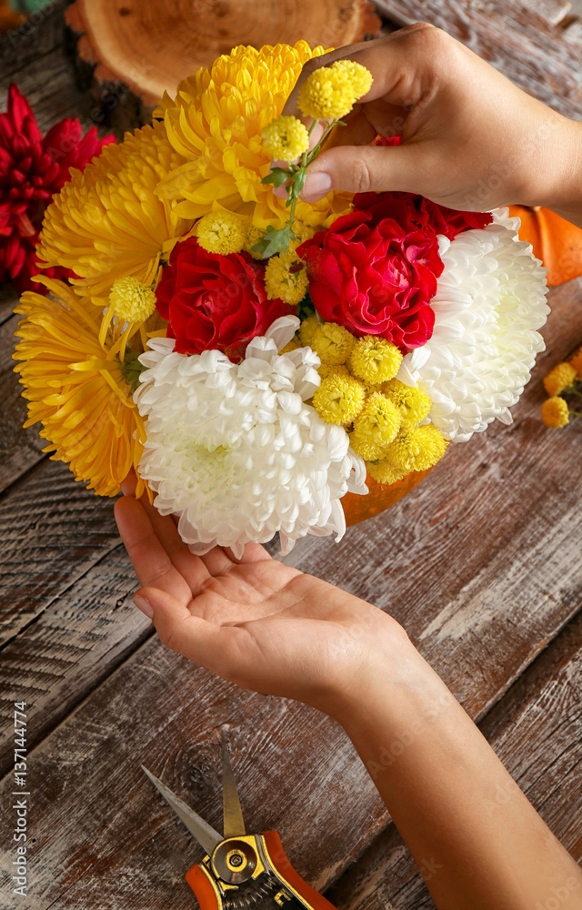 Florist at work. Home decoration with pumpkin and flowers on wooden background