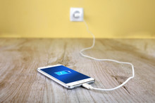 Mobile Smart Phones Charging On Wooden Desk