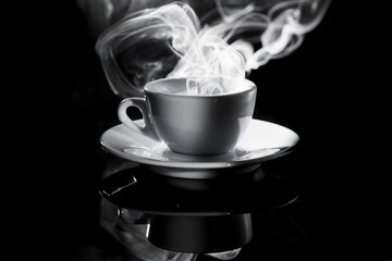 small white cup of steaming coffee on a black background