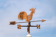 © milkovasa - Wooden rooster weathervane showing a wind direction. Traditional weathercock on heaven background. Decorative cock weathervane close up.