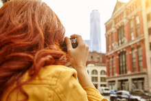 Young Female Tourist With Long Red Hair Photographing One World Trade Centre, Manhattan, New York, USA
