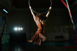© Connect Images - Young female acrobat poised hanging from hoop