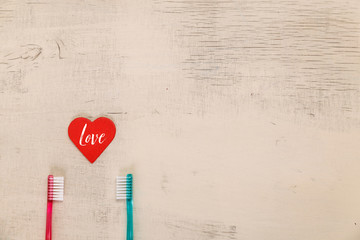 Love concept with hearts and toothbrushes. Love text. Valentines day design on wood vintage background. Wooden rustic board.