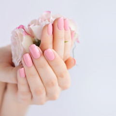 Wall Mural - Hands of a woman with pink manicure on nails and roses