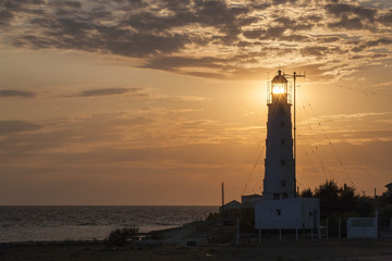 Wall Mural - view at the sea with sun lighting through lamp of lighthouse