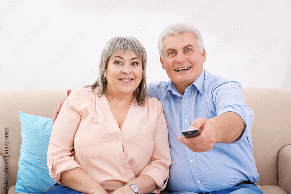 Middle aged couple watching TV at home
