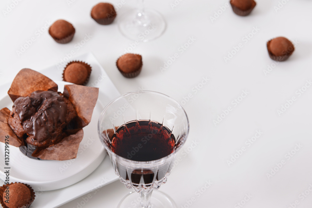 Delicious chocolate cake, truffles and red wine on white background