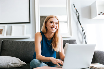 Cheerful woman using laptop and laughing at home