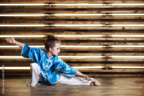 Zdjęcie XXL Całkiem mała dziewczynka w pokoju w sportowej odzieży dla sztuk walki to Wushu