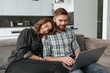 © Drobot Dean - Happy loving couple lies on sofa using laptop computer.