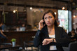 © Johnstocker - Beautiful business woman talking on cell phone looking at hand watch over cafe background.