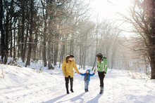 Little Boy Enjoying Playing With His Young Mom And Dad. Toddler Kid Holding Hands With Parents. Children Play Outdoors In Snow. Kids Sled In Winter Park. Outdoor Active Fun For Family Vacation.