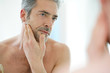 © goodluz - Portrait of mature man in front of mirror applying facial cream