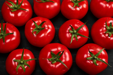 Tomato on a black background with realistic reflection and water drops. Fresh tomatoes