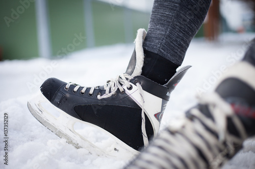 Fototapeta na szkło Young man hand commits laces on ice skates and prepare for ice skating