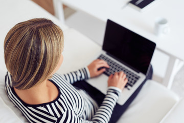 Rear view of young woman using laptop on sofa