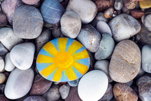 Sun Painted On Pebble With Stones Background