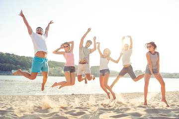 Poster - Group of happy young cheerful students jumping on the beach