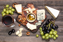 Grapes, Red Wine, Cheeses, Honey And Nuts Over Rustic Weathered Wood. Top View.
