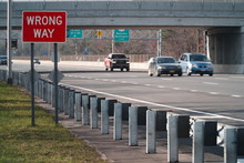 Wrong Way Caution Safety Sign Posted Along A Major Interstate Highway Facing The Opposite Direction Of Traffic To Avoid Car Vehicle Collision Accidents