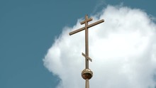 The Cross On The Dome Of An Orthodox Temple Against The Blue Sky With Clouds.