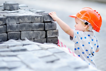 Little builder in hardhats with hammer working outdoors