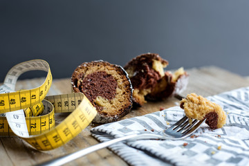 two pieces of bundt cake placed on a wooden table with a measuring tape next to them and a fork with a stuck piece of cake placed on a cloth