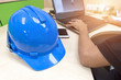 © ichzigo - Senior Engineer working about engineering with his laptop on the working desk..blue safety helmet and smart phone place on the working desk. Selective focus.