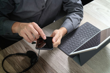Poster - top view of man hand using VOIP headset with digital tablet computer docking keyboard,smart phone,concept communication, it support, call center and customer service help desk on wooden table