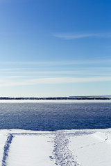 Wall Mural - Not frozen lake in the winter. Steam rises above the water. A bright blue sky.