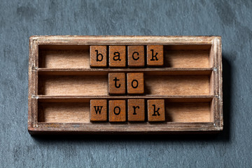 Back to work. Positive motivational quote. Vintage box, wooden cubes phrase with old style letters. Gray stone textured background. Close-up, up view, soft focus photo