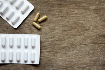 Brown capsule and white blister on wooden background (Concept for healthcare and drug addict with space)