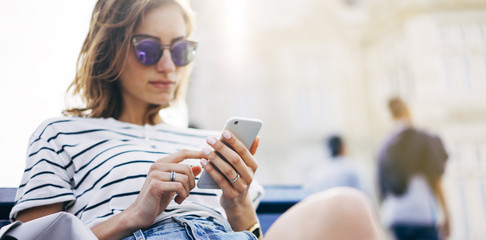 Wall Mural - Hipster texting message on smartphone or technology, mockup of blank screen. Girl using cellphone on building castle background close. Tourist female hands holding gadget on blurred summer backdrop