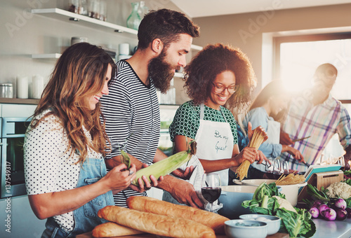 Friends preparing food at table in kitchen Tableau sur Toile