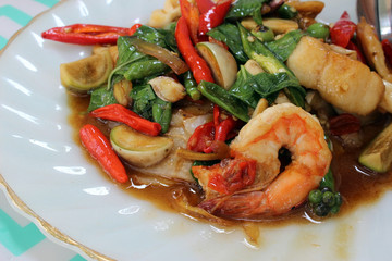 Close-up of a spicy asian shrimp and vegetables meal served on a plate. Thai name for this everyday cuisine is pad krapow goong / talay