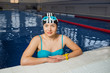 © Peakstock - Portrait of a female professional Swimmer wearing goggles and cap for swimming, looking at camera, being in the water