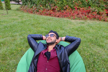 Wall Mural - Portrait of Young Arabic Male Man, Student Lies on Chair, Smilin