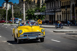 Fototapeta  - HDR - Auf der Hauptstrasse in Havanna Kuba fahrender amerikanischer gelber Cabriolet Oldtimer mit Touristen - Serie Kuba Reportage