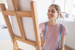 young woman artist drawing with the use of an easel