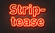 Striptease neon sign on brick wall background.