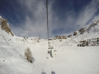 chairlift with skiers moving to the top of the mountain in a wonderful sunny day at the ski station Tonale, Ponte di Legno (Italy)