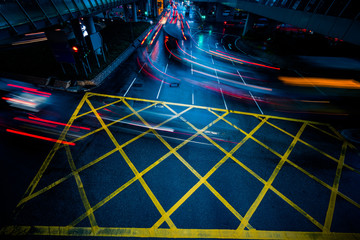 cars driving through yellow no parking area on asphalt street,blue toned,china.